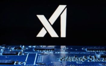 Elon Musk speaking at an event with xAI logo in the background