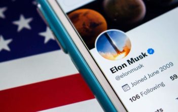 Elon Musk at podium with American flag and DOGE logo