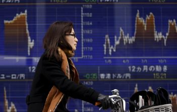 Traders monitoring stock market data on multiple screens in an Asian trading floor